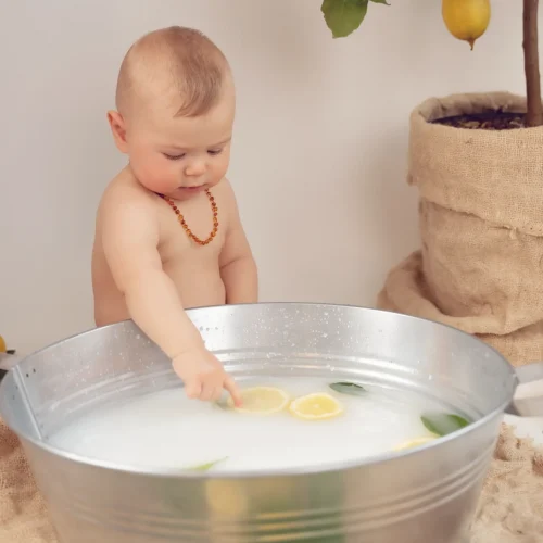 Baby zeigt auf einer Zitrone in der Badewanne