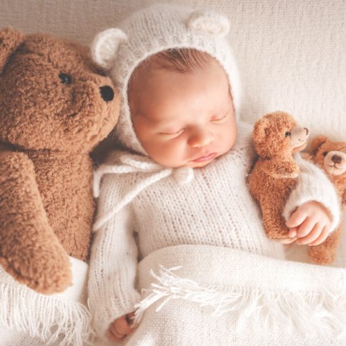 Baby Junge mit Bärenmütze und drei Kuschelbären