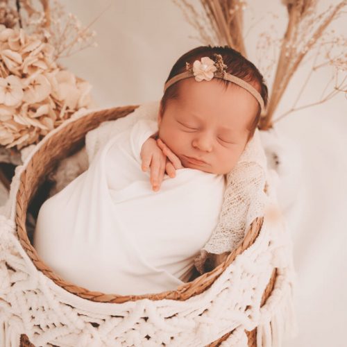 Baby Mädchen mit Haarband und Blumen im Hintergrund