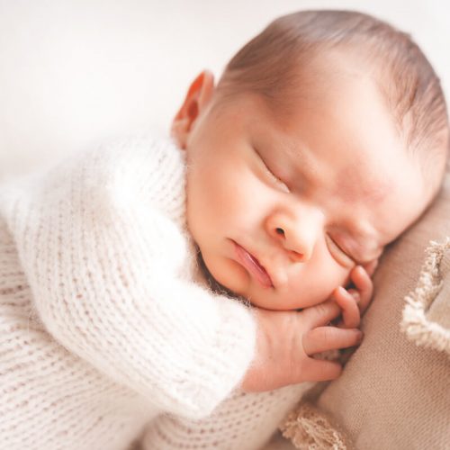 Baby mit Schmollmund und einem Herz auf dem Kissen