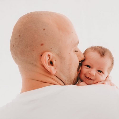 lächelndes Baby, was von seinem Papa geküsst wird