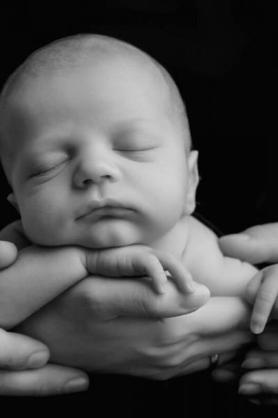 schwarz weiss Foto eines Neugeboren mit den Händen der Eltern