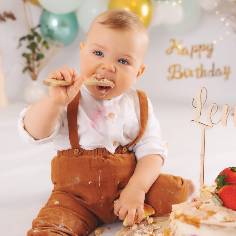 smash-cake-shooting, der Junge hat einen Holzlöffel mit Kuchen, seine Augen strahlen vor Freude